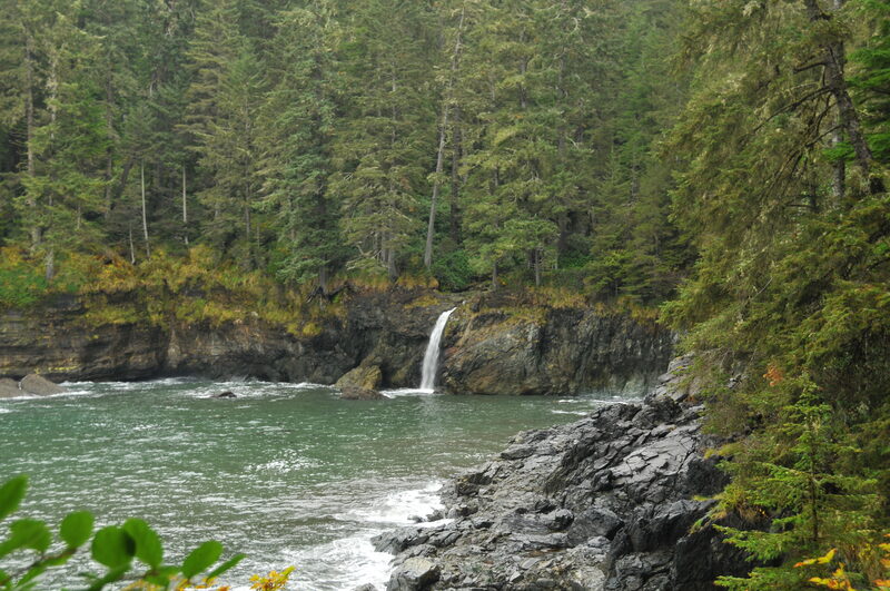 Waterfall into teal coastal inlet