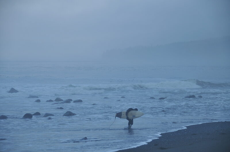 Surfer entering misty Pacific